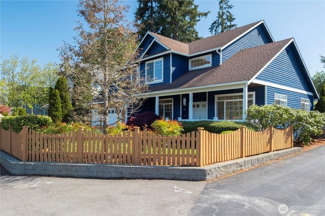 15704 124th Ave NE, Woodinville, WA 98072 - view of front of house featuring covered porch, a fenced front yard, and a shingled roof