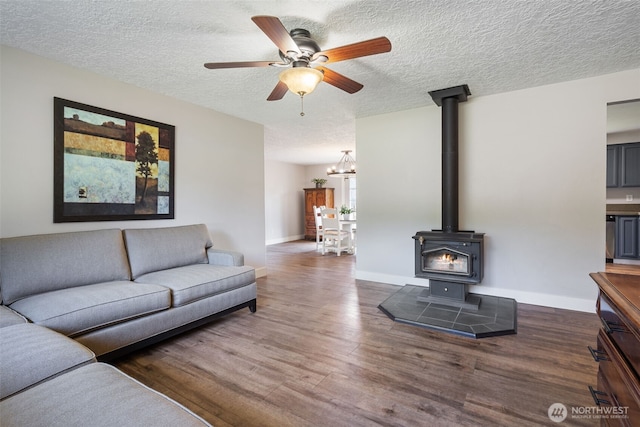 21803 NE Abernathy Rd, Yacolt, WA 98675 - living room featuring a wood stove, dark wood-type flooring, a textured ceiling, a chandelier, and a ceiling fan