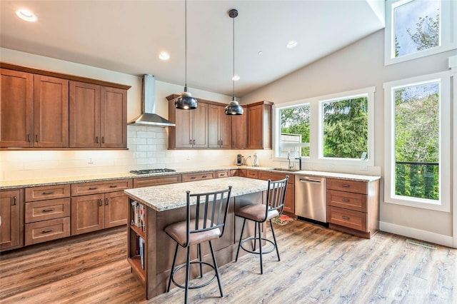 411 19th St NE Unit 9, East Wenatchee, WA 98802 - kitchen with wall chimney range hood, stainless steel appliances, a kitchen bar, light wood finished floors, and tasteful backsplash