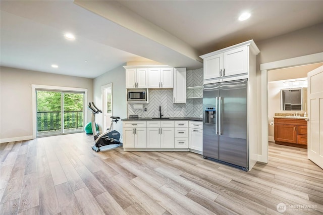 411 19th St NE Unit 9, East Wenatchee, WA 98802 - kitchen featuring appliances with stainless steel finishes, a sink, decorative backsplash, light wood-type flooring, and dark countertops