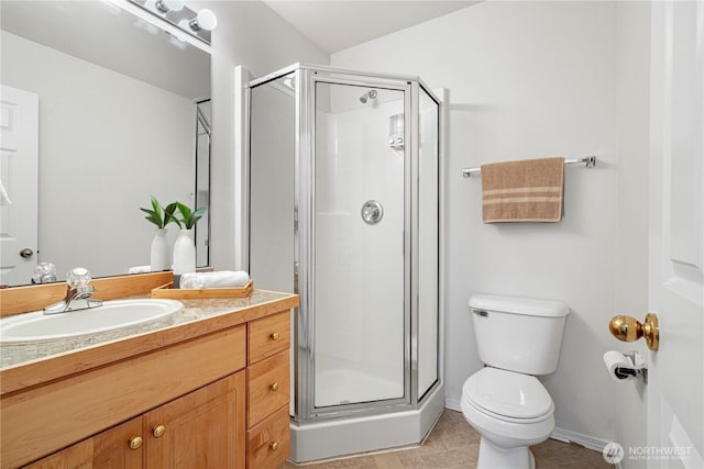 bathroom with a stall shower, toilet, vanity, and baseboards