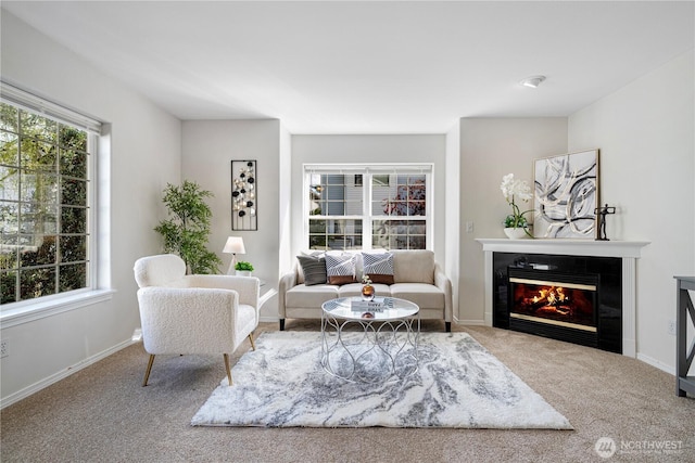 living room with carpet flooring, a glass covered fireplace, and baseboards
