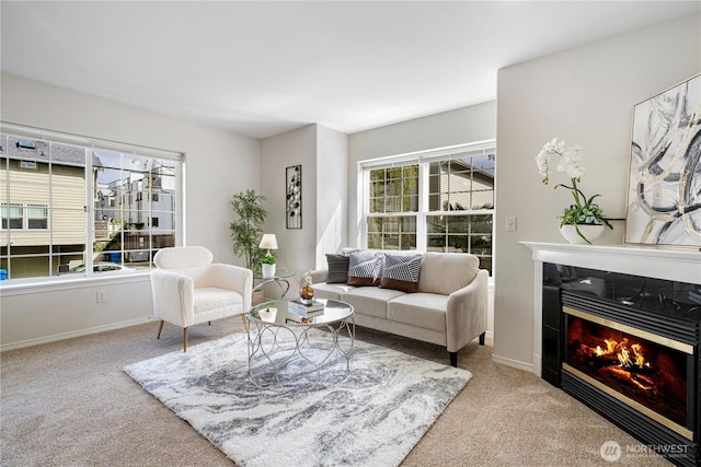 carpeted living area featuring baseboards and a glass covered fireplace