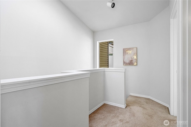 corridor with carpet flooring, baseboards, and lofted ceiling