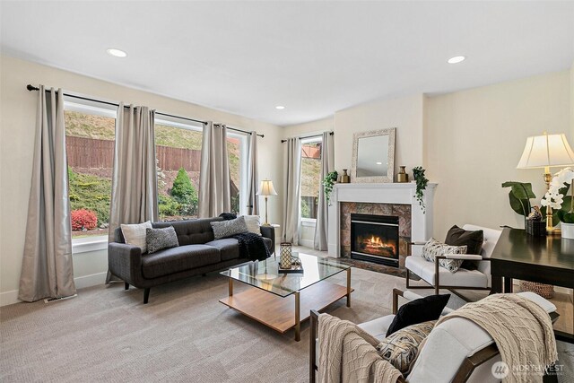 living area featuring a fireplace, light colored carpet, baseboards, and recessed lighting