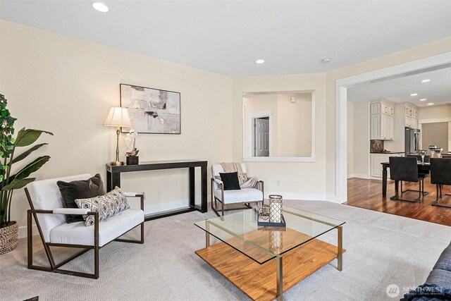 carpeted living room with recessed lighting, baseboards, and wood finished floors