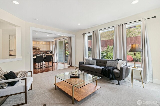 living area featuring recessed lighting, baseboards, and light colored carpet