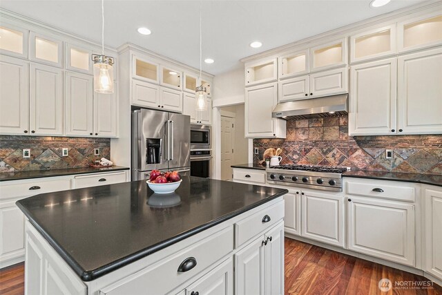 kitchen featuring appliances with stainless steel finishes, dark countertops, under cabinet range hood, a kitchen island, and decorative light fixtures