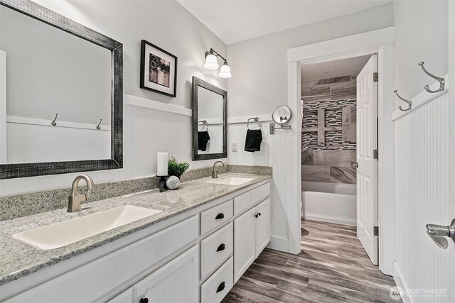 full bath with double vanity, wood finished floors, and bathing tub / shower combination