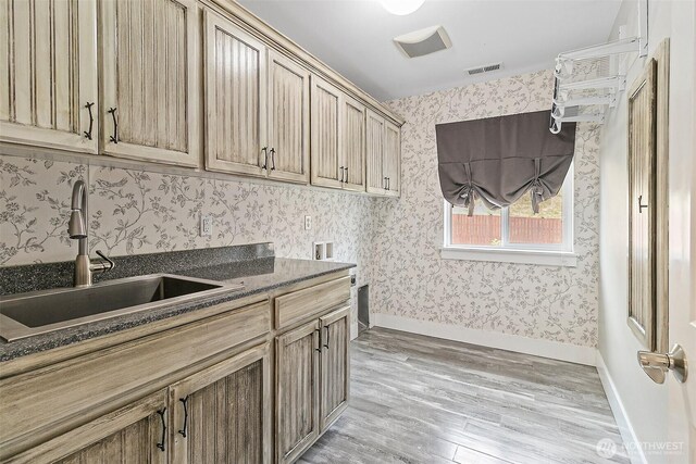 washroom featuring cabinet space, hookup for a washing machine, light wood-style floors, wallpapered walls, and baseboards