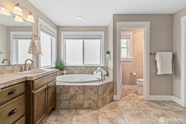 full bath with toilet, a bath, baseboards, and vanity