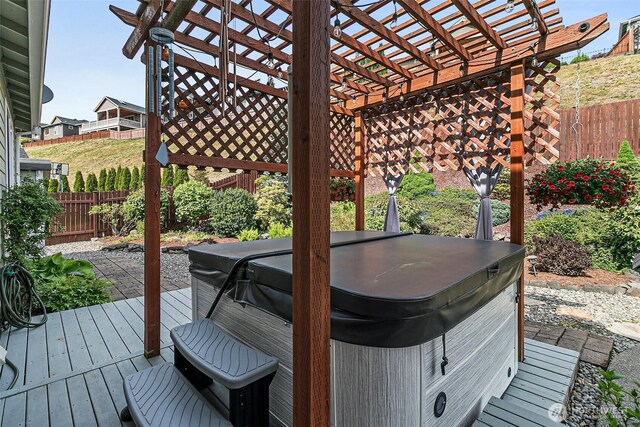 wooden deck with a hot tub, a fenced backyard, and a pergola