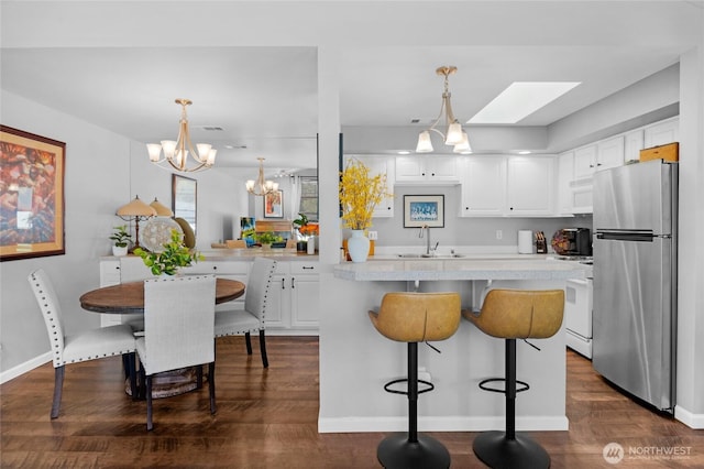 kitchen with white appliances, a sink, a chandelier, white cabinets, and light countertops