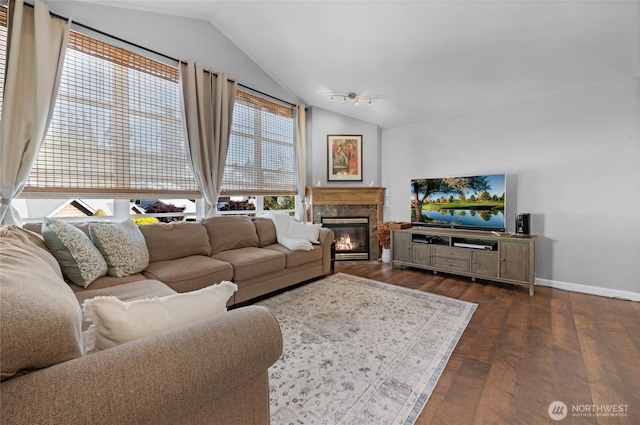 living room with lofted ceiling, dark wood-type flooring, baseboards, and a glass covered fireplace
