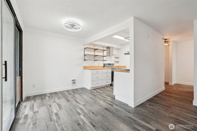 kitchen with stainless steel electric range, wood counters, wall chimney range hood, wood finished floors, and a textured ceiling