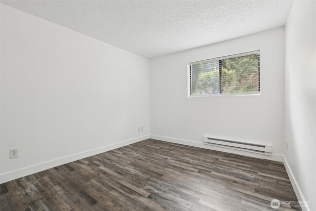 empty room featuring a baseboard heating unit, dark wood-style floors, a textured ceiling, and baseboards