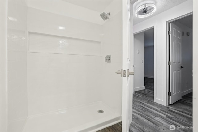 full bath featuring wood finished floors, a stall shower, and baseboards