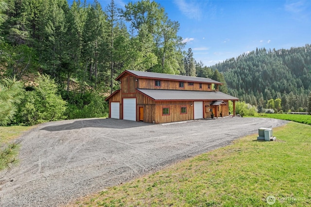 111 Connon Canyon Rd, Leavenworth, WA 98826 - chalet / cabin with a garage, a view of trees, metal roof, an outbuilding, and driveway