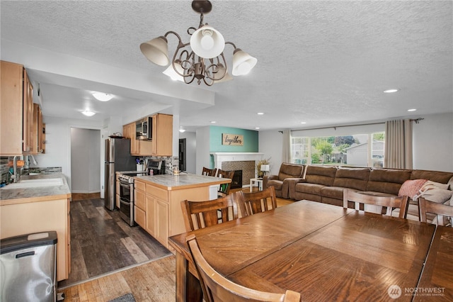 dining area featuring a chandelier, dark wood-style flooring, a textured ceiling, recessed lighting, and a fireplace