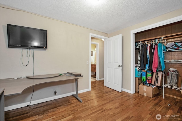 bedroom featuring wood finished floors, a textured ceiling, a closet, and baseboards
