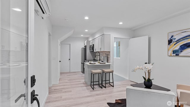911 Hiawatha Pl S, Seattle, WA 98144 - kitchen featuring a wall mounted air conditioner, appliances with stainless steel finishes, a breakfast bar area, light wood-type flooring, and decorative backsplash