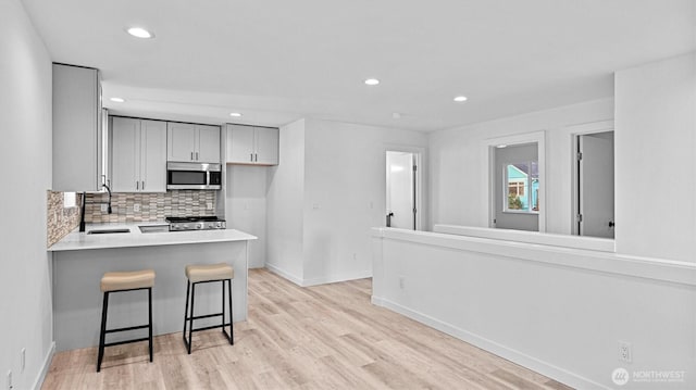 911 Hiawatha Pl S, Seattle, WA 98144 - kitchen featuring stainless steel microwave, range, a sink, tasteful backsplash, and light wood-type flooring
