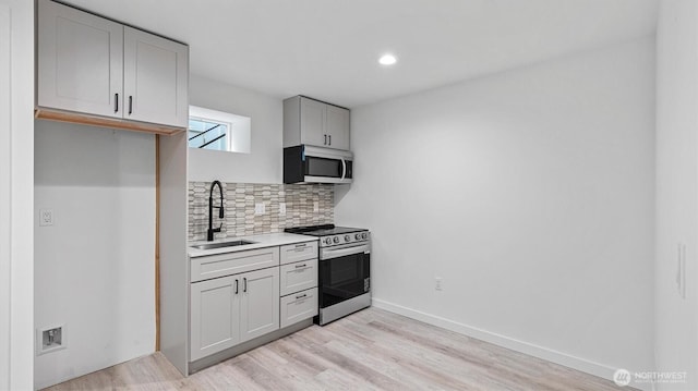911 Hiawatha Pl S, Seattle, WA 98144 - kitchen featuring appliances with stainless steel finishes, a sink, gray cabinets, backsplash, and light wood-style flooring