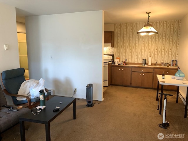 kitchen with wallpapered walls, electric range, light colored carpet, brown cabinetry, and decorative light fixtures