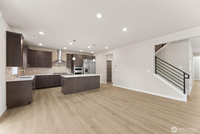 13436 NE 105th Ct Unit 17, Kirkland, WA 98033 - kitchen with wall chimney range hood, a sink, appliances with stainless steel finishes, a center island, and dark brown cabinetry