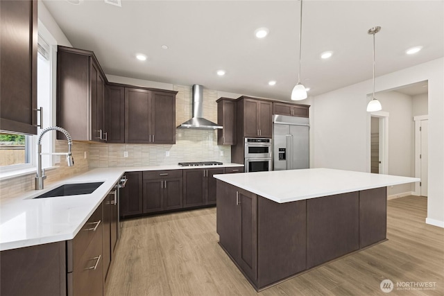 13436 NE 105th Ct Unit 17, Kirkland, WA 98033 - kitchen featuring wall chimney range hood, appliances with stainless steel finishes, a sink, dark brown cabinets, and light wood finished floors