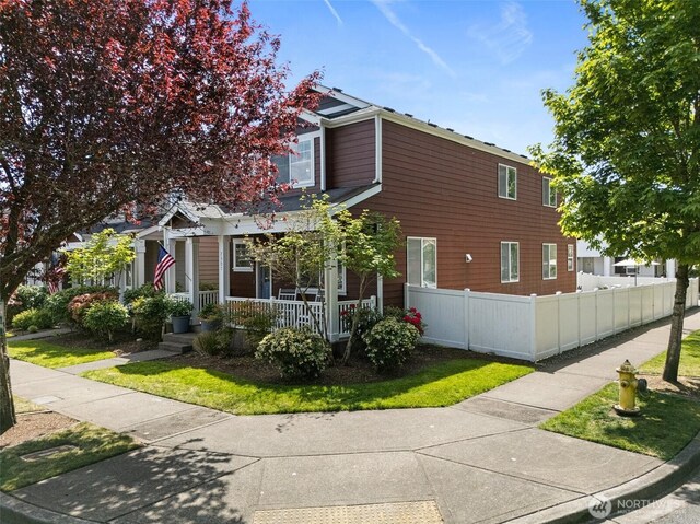 view of home's exterior with covered porch and fence