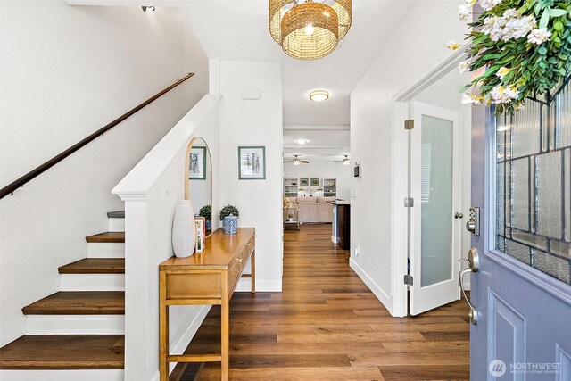 entrance foyer with stairway, wood finished floors, a chandelier, a ceiling fan, and baseboards