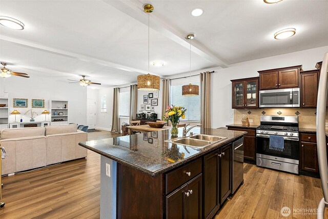 kitchen with stainless steel appliances, a sink, wood finished floors, ceiling fan, and beam ceiling