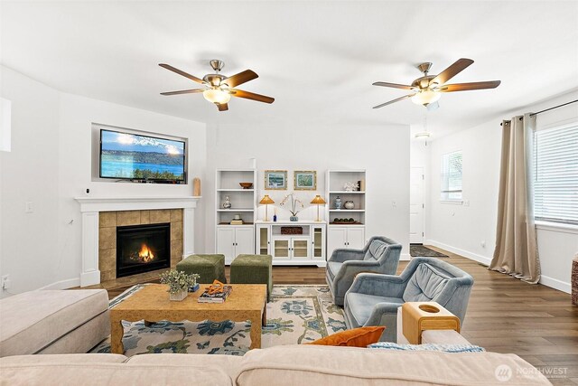 living area with a ceiling fan, baseboards, and wood finished floors