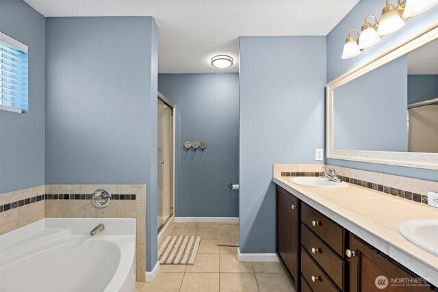 bathroom with a shower stall, tile patterned floors, double vanity, a bath, and baseboards