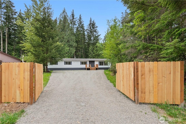 1071 Red Valley Ln, Maple Falls, WA 98266 - view of front of home with gravel driveway, fence, and a wooded view