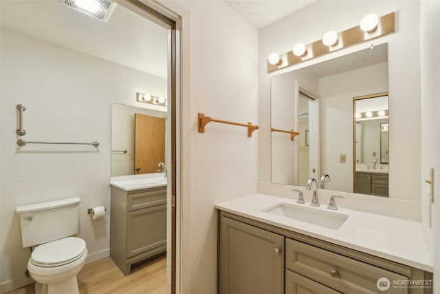 full bathroom with wood finished floors, two vanities, and toilet
