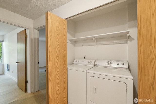 laundry room featuring washing machine and clothes dryer and light wood finished floors