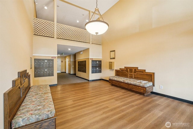 living area with high vaulted ceiling, mail area, wood finished floors, and baseboards