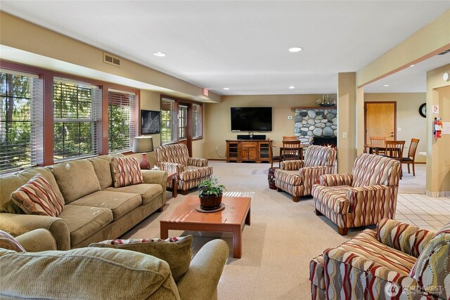 living area featuring recessed lighting, light carpet, and a stone fireplace