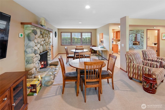 dining space with a stone fireplace, light carpet, and recessed lighting