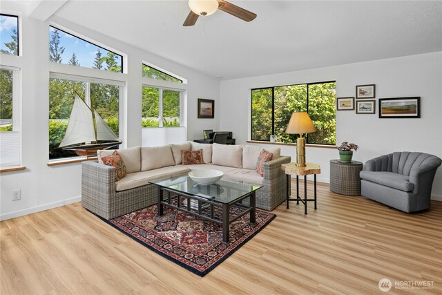 living room featuring lofted ceiling, ceiling fan, wood finished floors, and baseboards