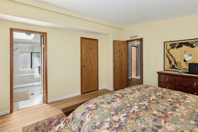 bedroom with wood finished floors, baseboards, and ensuite bathroom