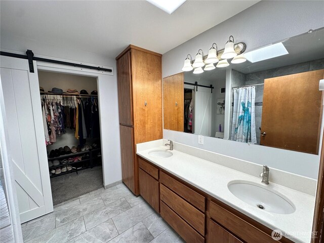 full bathroom with double vanity, a spacious closet, and curtained shower