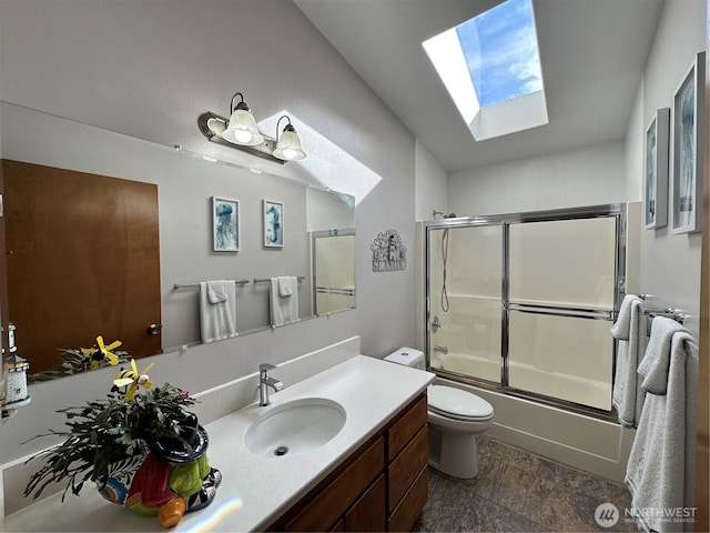 bathroom with a skylight, bath / shower combo with glass door, vanity, and toilet