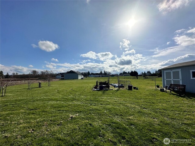 view of yard featuring a view of countryside, an outdoor structure, and a storage unit