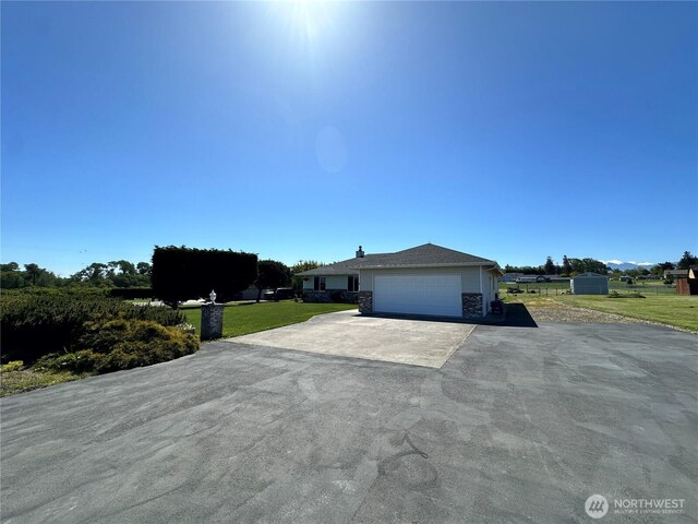 view of front of home with asphalt driveway, an attached garage, a front yard, and stone siding