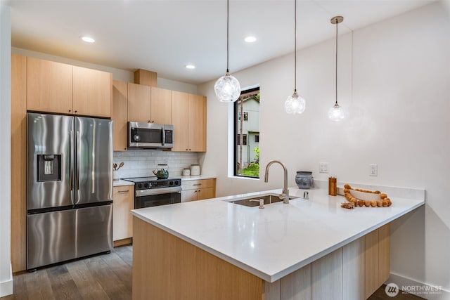 22513 Clearland Ln SE, Yelm, WA 98597 - kitchen with appliances with stainless steel finishes, a sink, a peninsula, light brown cabinets, and decorative backsplash