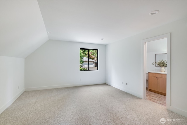 22513 Clearland Ln SE, Yelm, WA 98597 - unfurnished bedroom featuring light colored carpet, vaulted ceiling, baseboards, and connected bathroom