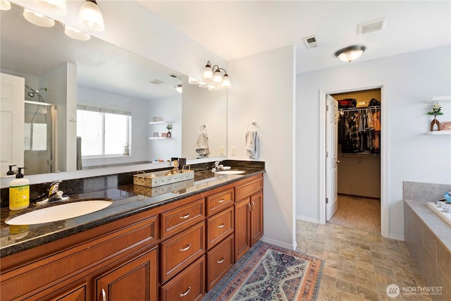19424 E 26th Avenue Ct E, Spanaway, WA 98387 - bathroom with a stall shower, double vanity, a walk in closet, a garden tub, and stone finish floors